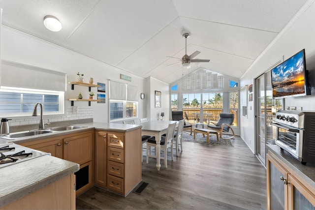 kitchen featuring a peninsula, a sink, vaulted ceiling, brown cabinets, and dark wood finished floors