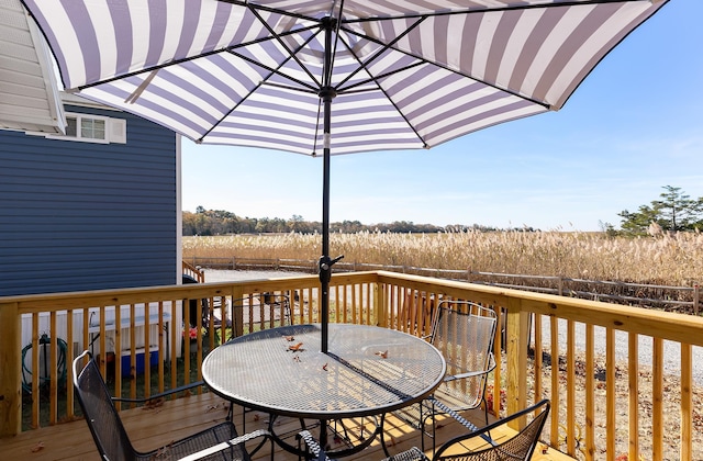 deck with outdoor dining space and a rural view