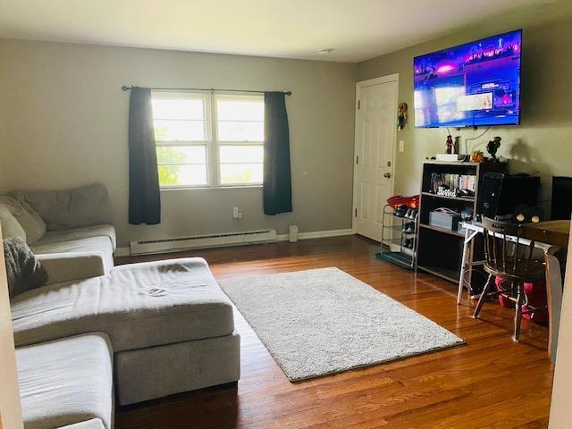 living room featuring baseboard heating and wood-type flooring