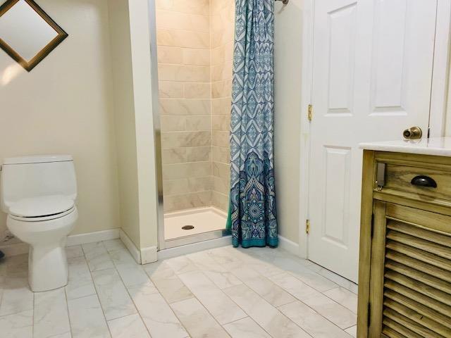 bathroom featuring tile patterned flooring, toilet, and curtained shower