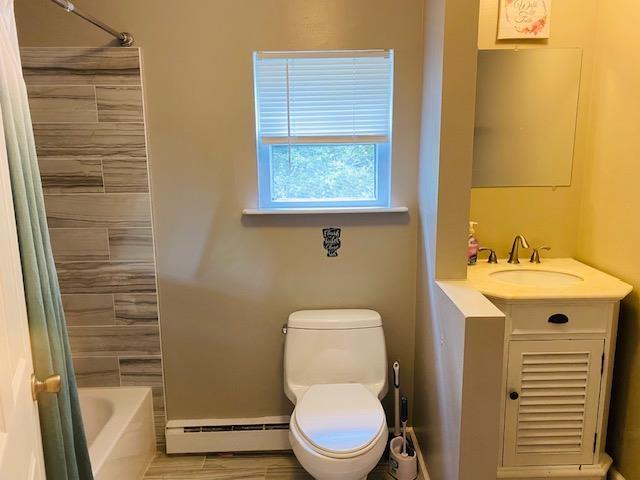 full bathroom with vanity, a baseboard radiator, toilet, and tiled shower / bath