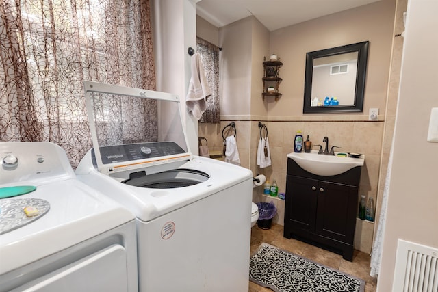 222 E 2nd Ave, North Wildwood, NJ 08260 - washroom with washing machine and dryer, light tile patterned flooring, tile walls, and a wainscoted wall