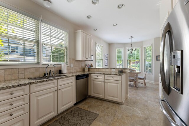 kitchen featuring white cabinetry, sink, stainless steel appliances, kitchen peninsula, and pendant lighting