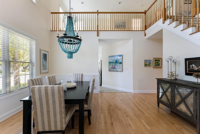 dining room featuring a towering ceiling, light hardwood / wood-style floors, and a notable chandelier