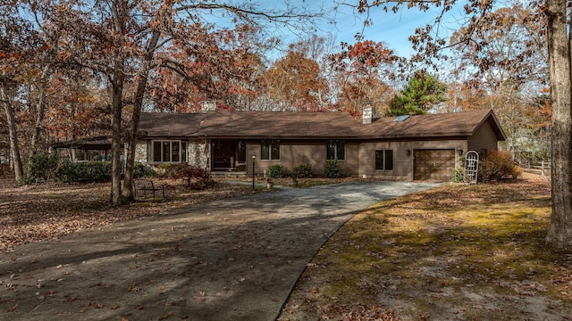 ranch-style house with a garage, a chimney, and concrete driveway