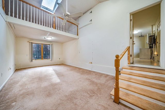 unfurnished living room with a ceiling fan, a skylight, a healthy amount of sunlight, and light carpet