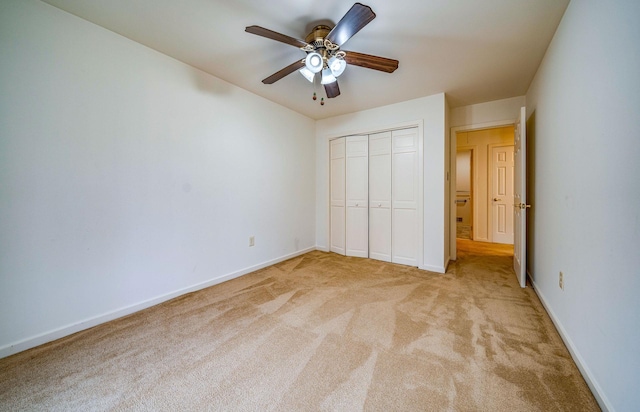 unfurnished bedroom featuring ceiling fan, a closet, light colored carpet, and baseboards