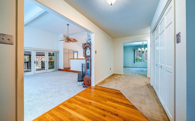 hallway featuring light carpet, vaulted ceiling with beams, a chandelier, and baseboards