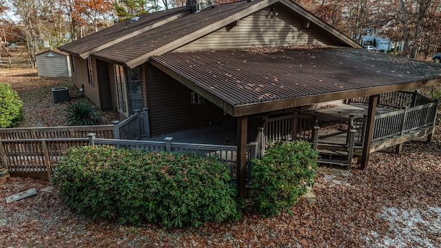 view of side of property with metal roof, cooling unit, and a wooden deck