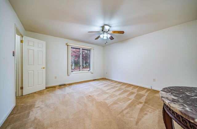 empty room featuring baseboards, a ceiling fan, and light colored carpet