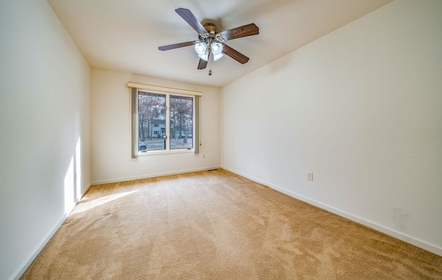 empty room featuring a ceiling fan, light carpet, and baseboards