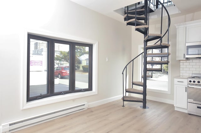 foyer with a baseboard heating unit, stairway, light wood-style flooring, and baseboards