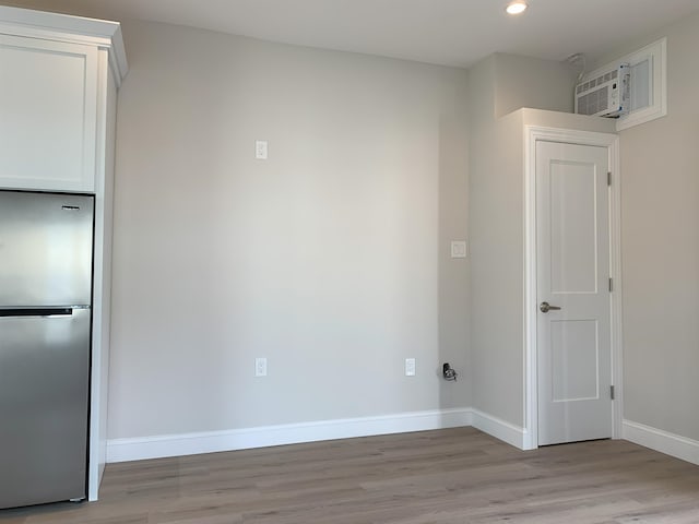 interior space featuring light wood-type flooring, recessed lighting, a wall unit AC, and baseboards