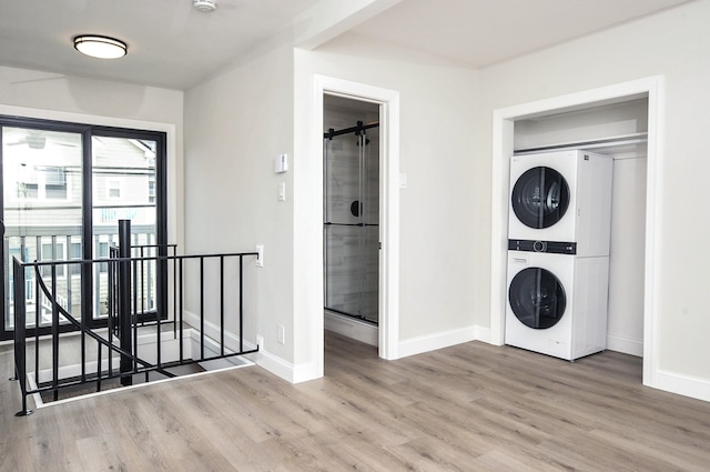 washroom featuring laundry area, baseboards, light wood-style floors, and stacked washer / dryer