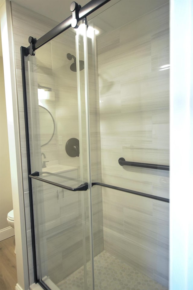 bathroom with toilet, a shower stall, and wood finished floors