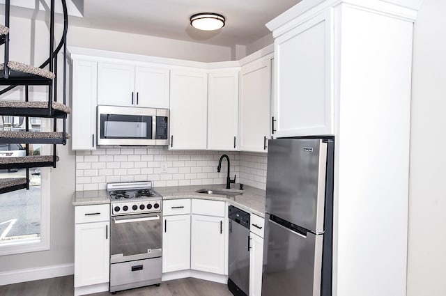 kitchen featuring backsplash, white cabinetry, stainless steel appliances, and a sink