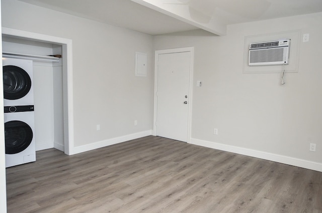 interior space featuring a wall mounted AC, wood finished floors, and stacked washer and clothes dryer