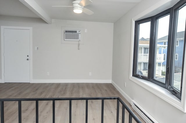 spare room featuring baseboards, a wall unit AC, a baseboard radiator, beamed ceiling, and wood finished floors