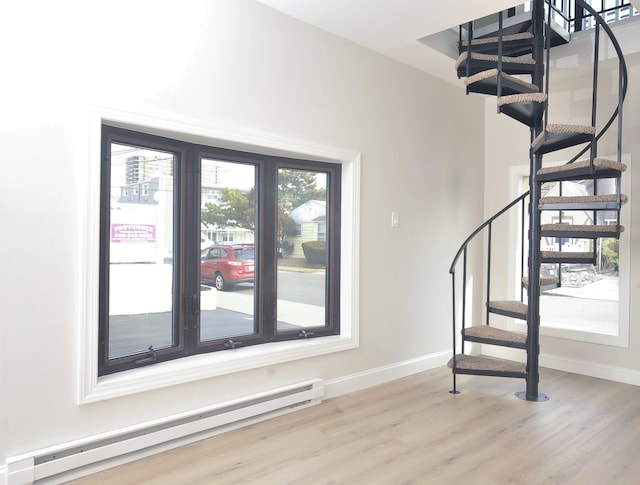 entryway featuring baseboards, stairway, baseboard heating, and wood finished floors