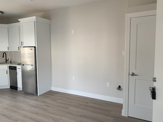 kitchen with white cabinets, tasteful backsplash, stainless steel appliances, and a sink