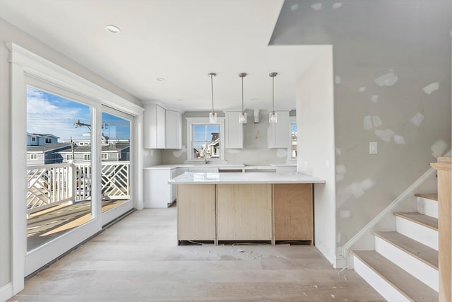 kitchen featuring white cabinetry, decorative light fixtures, kitchen peninsula, and light wood-type flooring