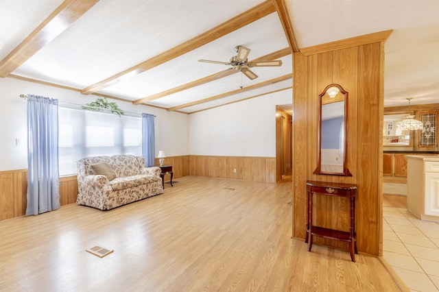 living area featuring wooden walls, a wainscoted wall, ceiling fan, and visible vents