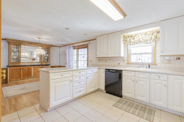 kitchen with tasteful backsplash, dishwasher, a sink, light countertops, and a peninsula