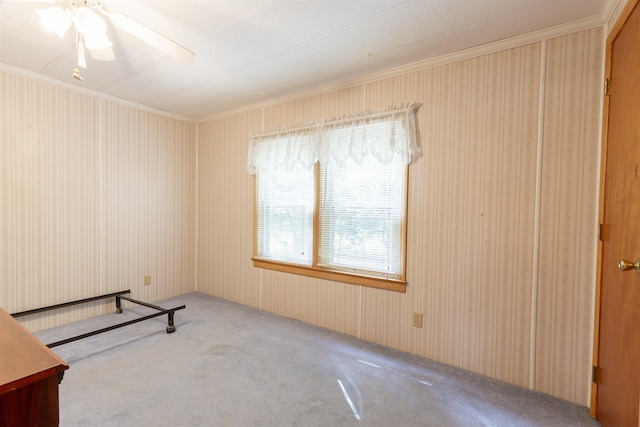 carpeted spare room featuring ornamental molding and a ceiling fan