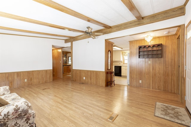 living area featuring a ceiling fan, wood walls, beam ceiling, and light wood-type flooring