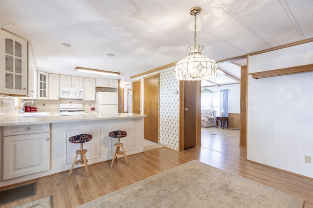 kitchen with an inviting chandelier, a sink, glass insert cabinets, white appliances, and light wood-style flooring