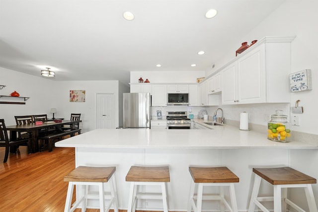 305 E Bennett Ave Unit A, Wildwood, NJ 08260 - kitchen with appliances with stainless steel finishes, a peninsula, light countertops, white cabinets, and light wood-style floors