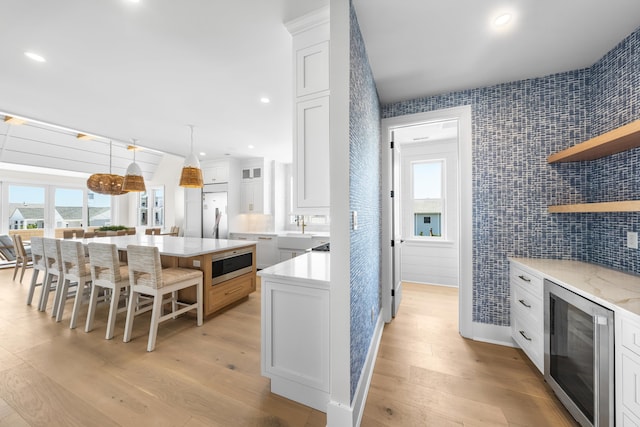 242 83rd St, Stone Harbor, NJ 08247 - kitchen with beverage cooler, open shelves, white cabinets, a breakfast bar, and refrigerator