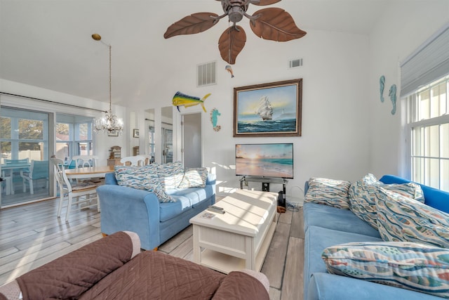 living area with ceiling fan with notable chandelier, lofted ceiling, visible vents, and wood finished floors