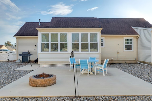 back of property featuring roof with shingles, a patio, a fire pit, and fence