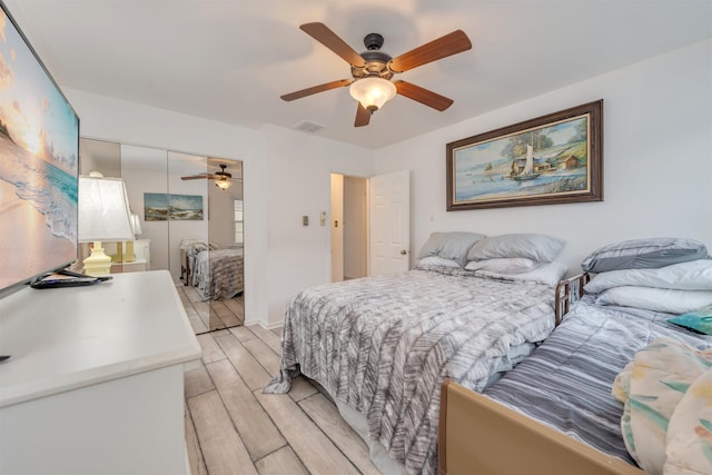 bedroom with light wood-style floors, ceiling fan, visible vents, and a closet