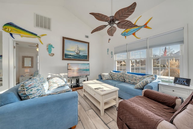 living area featuring high vaulted ceiling, light wood-type flooring, visible vents, and a ceiling fan