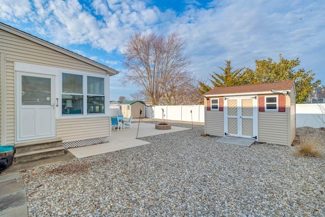 view of yard with entry steps, a patio, a fenced backyard, a fire pit, and a storage unit