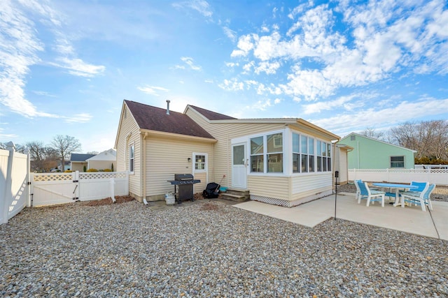 back of property featuring entry steps, a sunroom, a fenced backyard, a gate, and a patio area