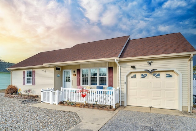 ranch-style house featuring an attached garage, driveway, a shingled roof, and a porch