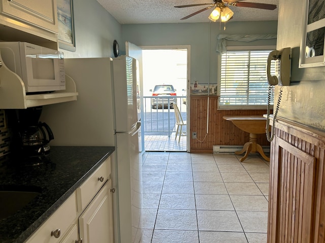 kitchen with a baseboard heating unit, white cabinetry, a textured ceiling, and light tile patterned floors