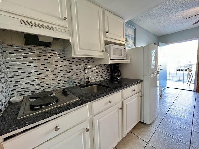 kitchen with white appliances, white cabinetry, a sink, and under cabinet range hood