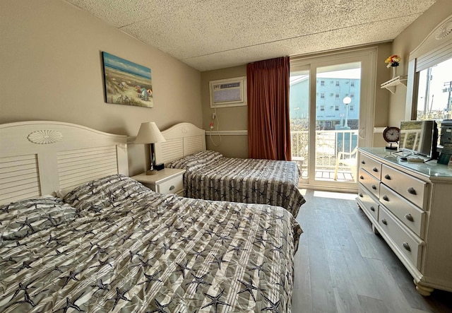 bedroom featuring access to outside, dark wood-type flooring, a wall mounted air conditioner, and a drop ceiling