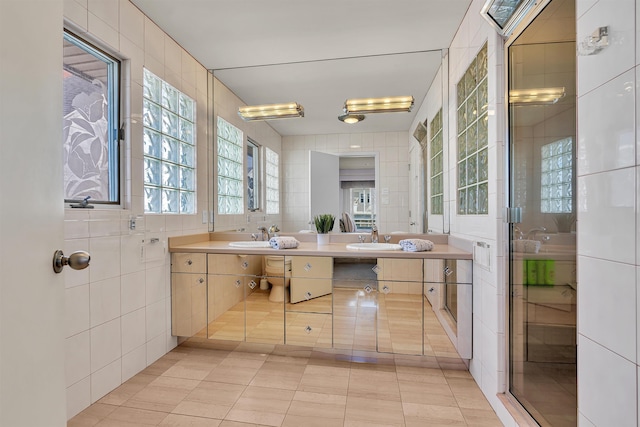 full bath with tile walls, double vanity, tile patterned floors, and a sink