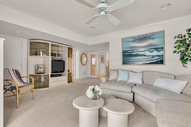 living area with visible vents, light colored carpet, and a ceiling fan