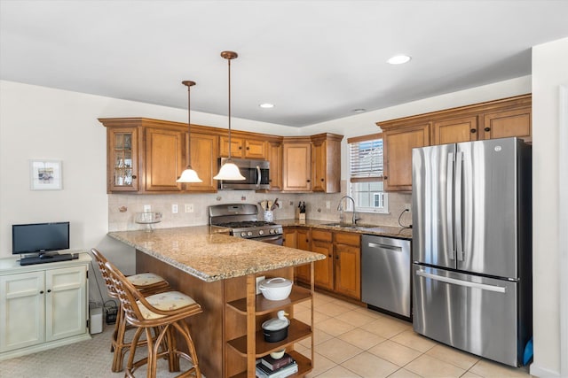 kitchen featuring a peninsula, brown cabinets, stainless steel appliances, and a sink