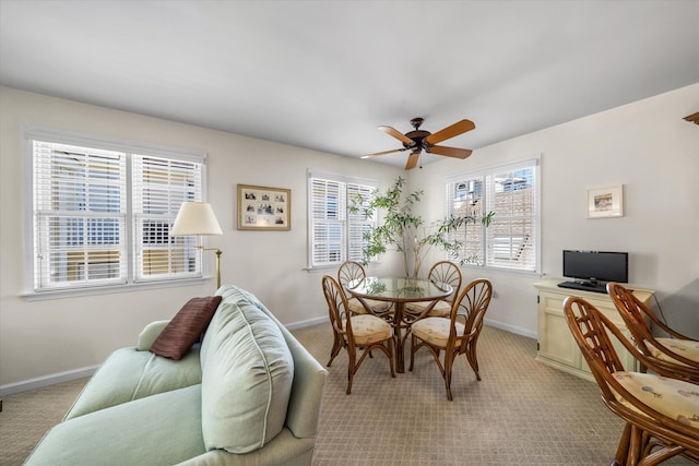 dining room with baseboards, a ceiling fan, and light colored carpet