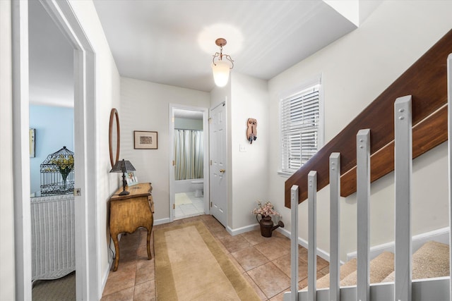 entrance foyer with light tile patterned floors, stairs, and baseboards