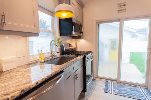 kitchen with light stone countertops, plenty of natural light, appliances with stainless steel finishes, and a sink