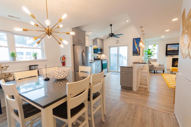 dining space with light wood-style floors, visible vents, vaulted ceiling, and a wealth of natural light