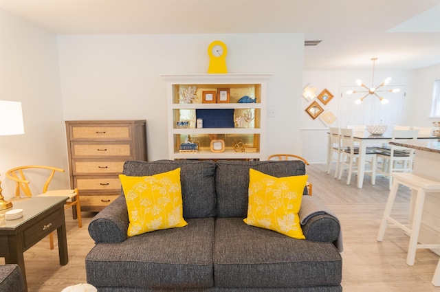 living area featuring a chandelier, light wood-type flooring, and visible vents